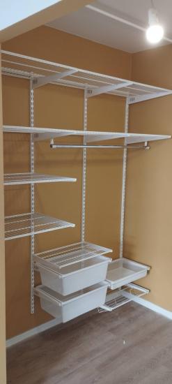 Установлена система хранения с металлическими полками и выдвижными корзинами на стене. Стеллажи закреплены, обеспечивая функциональность и удобство использования в интерьере.