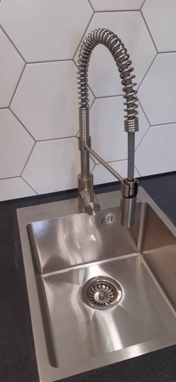 Установлена кухня с мойкой, смесителем и столешницей из ДСП. Все элементы подогнаны, подключены коммуникации, проведена герметизация. Завершён монтаж фартука из плитки.