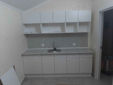 Установлена кухонная поверхность с вырезом под мойку, точно подогнана по размеру, закреплена на шкафах. Все элементы гармонично сочетаются, обеспечивая функциональность и эстетику.