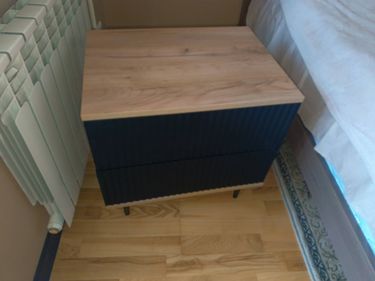 Собрана компактная тумба: установлены ножки, прикреплены боковые панели, закреплена верхняя крышка, выдвижные ящики вставлены. Все элементы надежно зафиксированы, конструкция устойчива.