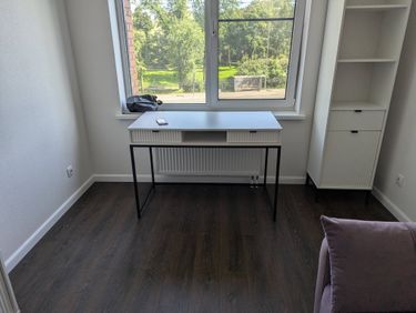 В комнате установлен высокий белый стеллаж с полками и дверцами, обеспечивающий удобное хранение. Работа завершена аккуратно, мебель надежно закреплена и готова к использованию.