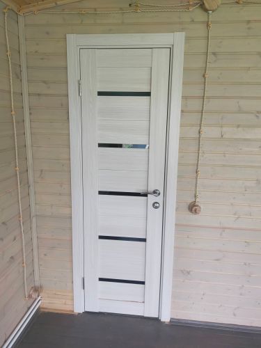 Установлена светлая дверь с горизонтальными вставками, закреплены петли, врезан замок, прикреплена ручка, отрегулирована коробка, зазоры устранены, обеспечена плавная работа.