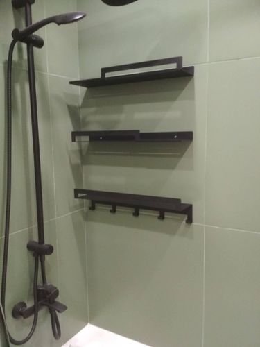 Установлены три черные полки в ванной комнате на зеленую плитку, закреплены надежно, расположены вертикально. Под нижней полкой крючки для полотенец.