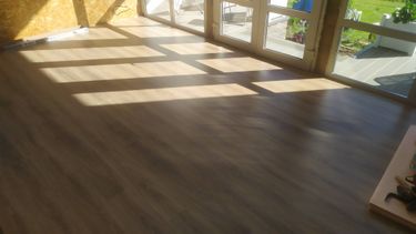 На ровное основание уложено покрытие, обеспечивая гладкую и эстетичную поверхность. Все панели аккуратно состыкованы, создавая единый и гармоничный вид в помещении.