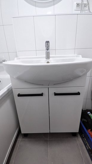 Установлена новая раковина с подключением к водопроводу и канализации. Смеситель закреплён, обеспечено герметичное соединение, проверена функциональность. Шкафчик под раковиной собран и установлен.