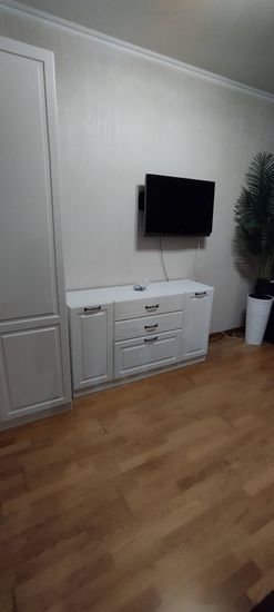 Собран белый комод с тремя ящиками и двумя дверцами. Установлены ручки, выровнены фасады, закреплены элементы. Комод устойчиво стоит на полу, готов к использованию.