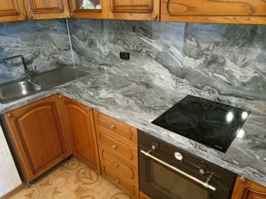 Изображена кухня с деревянными шкафами, мраморной столешницей и варочной панелью. Установлена новая сантехника и электрическая плита. Завершены работы по обновлению интерьера.