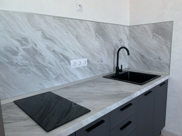 Установлены пластиковые панели на стены кухни. Поверхность облицована материалом с мраморным узором. Завершён монтаж, обеспечивающий эстетичный и практичный вид помещения.