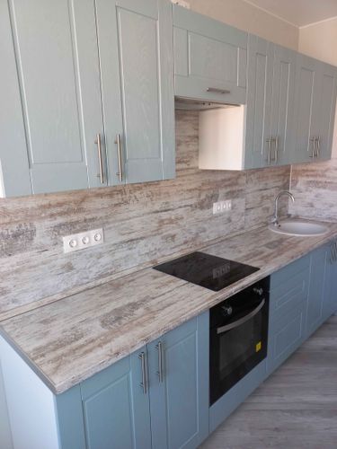 Собрана кухня: установлены шкафы, закреплены дверцы, смонтирована столешница, подключена варочная панель, раковина с краном, выполнена отделка фартука. Все элементы надежно зафиксированы.