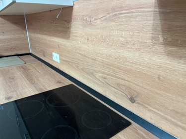 Выполнена установка кухонной поверхности с вырезами для варочной панели и мойки, точно подогнанными к стене. Результат — гладкая, ровная поверхность без зазоров.