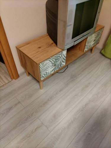 Собран деревянный стеллаж с двумя отделениями и ножками. Установлены декоративные панели с растительным узором. Готовая конструкция размещена на светлом полу.