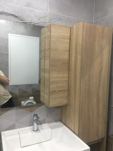 Установлены шкафы из дерева, закреплены на стене, смонтировано зеркало, раковина с краном подключена, проведены коммуникации, завершена отделка плиткой.