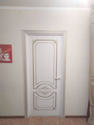 Изображена установленная дверь с декоративными элементами. Работа включает монтаж конструкции, фиксацию направляющих, крепление петель, регулировку створок для плавного открывания и закрывания.