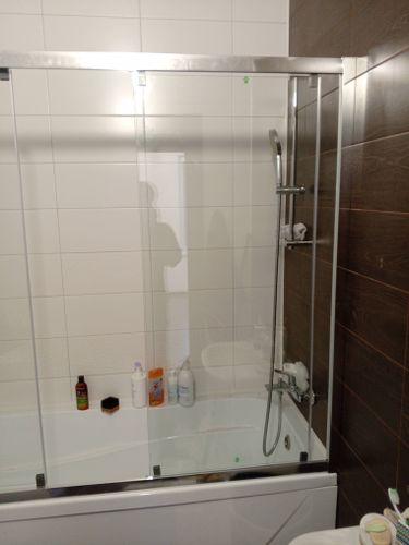 Установлена новая стальная ванна, закреплены стеклянные шторки, подключены смеситель и душ, герметизированы швы, проверена система слива, выровнены поверхности, завершена отделка стен.