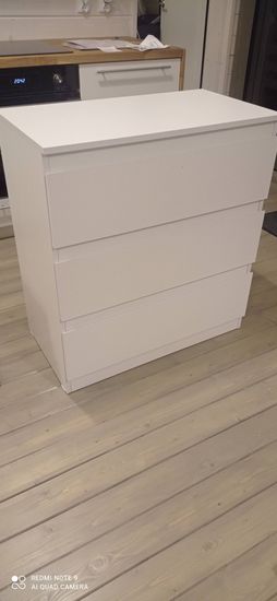 Собран новый белый комод с тремя выдвижными ящиками. Установлены все детали, обеспечена устойчивость конструкции, проверена функциональность механизмов. Готов к использованию.