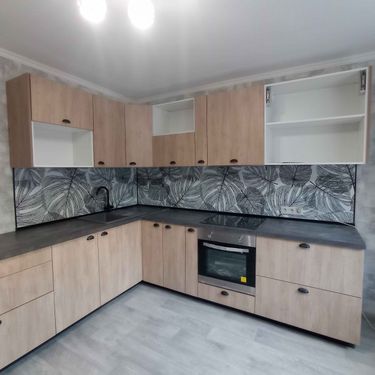 Установлены шкафы, закреплена столешница, подключена варочная панель, смонтирован фартук с узором, установлена раковина, размещены ручки на дверцах, выровнены поверхности.