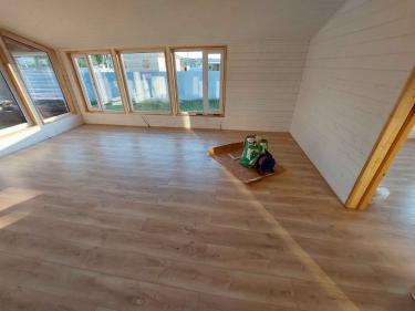 В комнате уложено новое покрытие, обеспечивающее ровную и гладкую поверхность. Светлые панели гармонично сочетаются с интерьером, создавая уютную атмосферу.