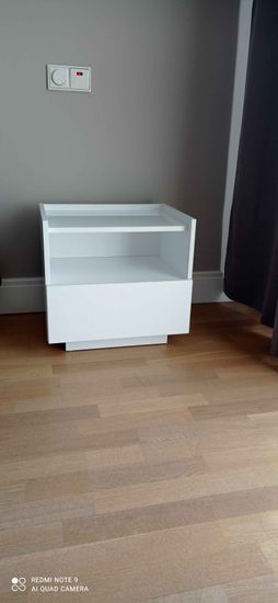 Собрана белая тумба с выдвижным ящиком и открытой полкой. Все элементы аккуратно соединены, конструкция устойчива и готова к использованию.