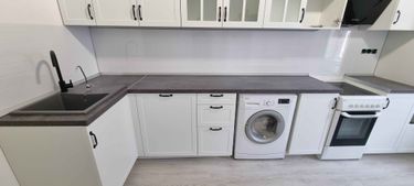 Установлены шкафы, закреплены фасады, смонтирована столешница, подключены мойка и техника, установлены ручки, выполнена подгонка всех элементов, обеспечена функциональность и эстетика.