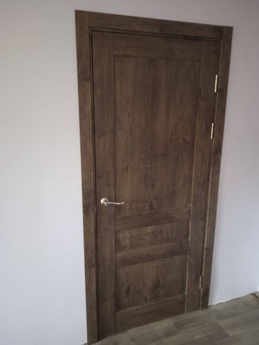 Установлена деревянная створка, закреплены петли, врезана ручка, выровнена коробка, проведена регулировка, проверена плавность открывания и закрывания, завершена отделка наличниками.