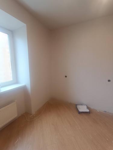 Комната обновлена: стены покрыты свежим слоем краски, поверхность ровная и гладкая, углы аккуратно обработаны. Пол чистый, без следов работы, интерьер выглядит светлым и опрятным.