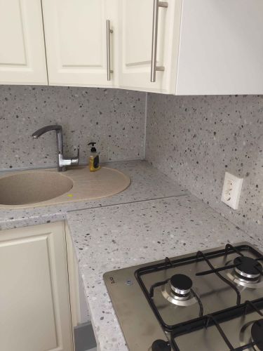 Установлена столешница с вырезами для мойки и варочной панели, подогнана к стене, обеспечена точная подгонка и аккуратные швы, поверхность гладкая и ровная, готова к использованию.