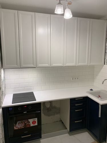 Установлена белая столешница, идеально подогнанная по размерам кухни. Выполнены вырезы для варочной панели и мойки, обеспечена надежная фиксация. Поверхность ровная, без зазоров.