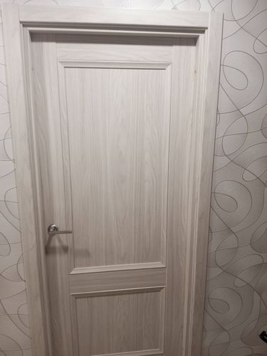 Установлена светлая дверь с ручкой, закреплена коробка, отрегулированы петли, обеспечена плавная работа, добавлены наличники, завершена отделка проема.