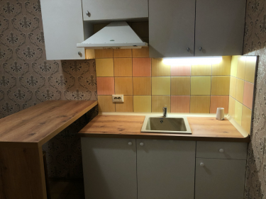 Установлены шкафы, смонтирована столешница, врезана мойка, подключен смеситель, закреплена вытяжка, собраны и навешены фасады, установлены полки, подключено освещение, завершена отделка.