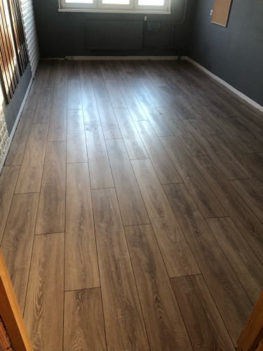 На ровное основание уложено ламинированное покрытие, создающее гладкую и эстетичную поверхность. Полотно плотно прилегает, обеспечивая долговечность и стильный вид помещения.