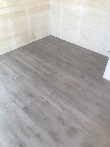 На полу уложено новое покрытие, светлые панели аккуратно подогнаны, поверхность ровная и гладкая, стыки незаметны, общий вид обновлённого интерьера стал более современным и свежим.