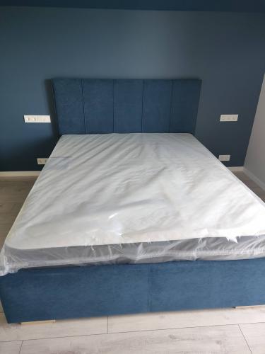 Собрана новая двуспальная конструкция: установлено изголовье, закреплены боковые панели, уложен матрас. Все элементы надежно соединены, обеспечивая устойчивость и комфорт.