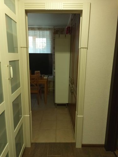 Выполнена установка декоративной арки в дверном проеме. Конструкция гармонично вписана в интерьер, обеспечивая плавный переход между помещениями. Завершено оформление проема с отделкой.