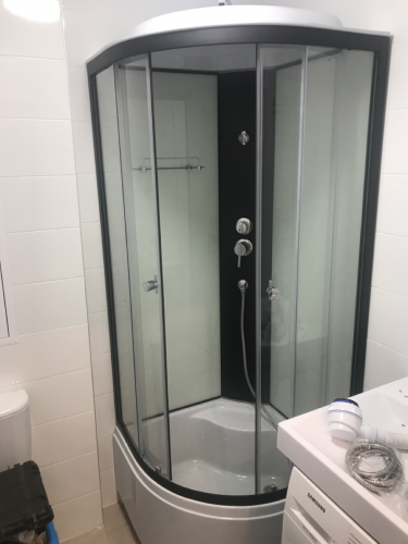 Установлена современная душевая конструкция с низким основанием. Смонтированы стеклянные панели, подключены водопроводные элементы, герметично зафиксированы соединения, проверена функциональность.