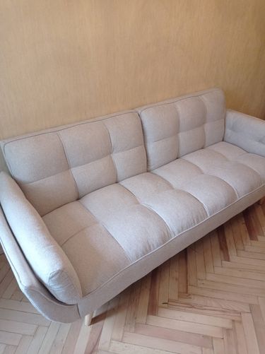 Собран диван: установлены ножки, прикреплены подлокотники, закреплены спинки и подушки. Все элементы надежно соединены, конструкция устойчива, готова к использованию.