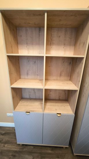 Собран прочный стеллаж с полками и дверцами. Установлены все детали, обеспечена устойчивость конструкции. Завершена установка в помещении, проверена функциональность.