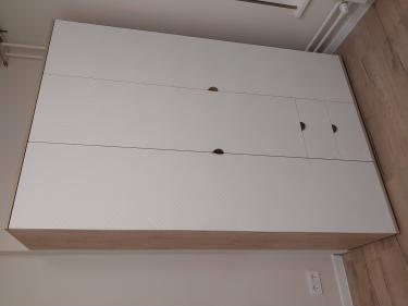 Собран шкаф с тремя дверцами и двумя выдвижными ящиками. Установлены петли, ручки, выровнены фасады. Конструкция устойчива, готова к использованию.