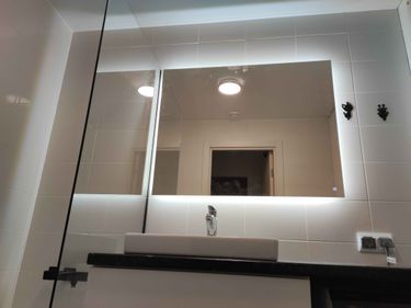 Зеркало установлено на стену ванной комнаты, закреплено надежно, ровно. Подключена подсветка, обеспечивающая равномерное освещение. Все работы выполнены аккуратно и качественно.