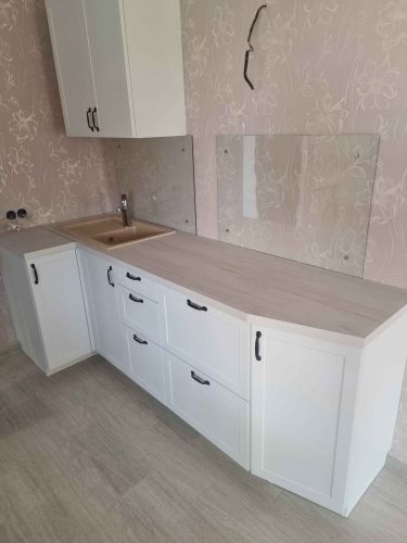 Установлены шкафы, закреплены фасады, смонтирована столешница, врезана мойка, подключен смеситель, прикреплены ручки, установлены стеклянные панели на стену.