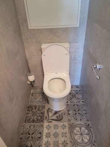 Установлено сантехническое оборудование на плиточный пол, подключены коммуникации, закреплена крышка, проверена герметичность, добавлены аксессуары, выполнена уборка.