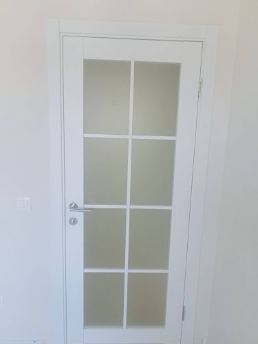Установлена белая дверь с матовым стеклом, закреплены петли, врезана ручка, отрегулирована фурнитура, обеспечена плавность закрывания, выполнена подгонка по уровню, завершена отделка проема.