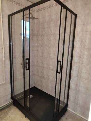 Установлена стеклянная конструкция с черными рамами, закреплены двери, подключен душевой лейка, герметизация швов, проверена устойчивость, произведена настройка всех элементов.