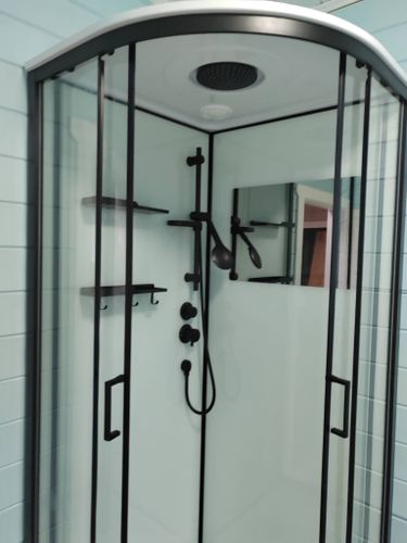 Установлена современная душевая конструкция с низким основанием, герметично закреплены стеклянные панели, смонтированы дверцы, подключены водопроводные элементы, проверена функциональность системы.