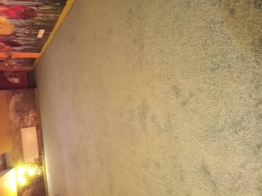 На полу уложено покрытие из ковровых плиток, образуя ровную поверхность. Все элементы аккуратно состыкованы, создавая цельный вид. Стены оформлены яркими обоями с цветочным узором.