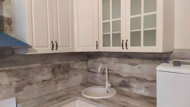 Установлены шкафы, закреплены фасады, смонтирована столешница, подключена раковина, установлены ручки, выполнена облицовка стен. Завершена сборка и установка кухонного гарнитура.