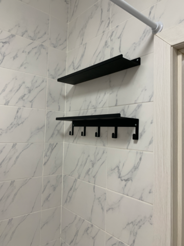 Установлены две черные полки на стене с мраморной плиткой. Верхняя простая, нижняя с крючками для подвешивания. Работа выполнена аккуратно, крепление надежное.