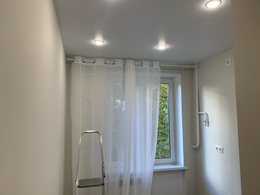 На стене закреплён карниз, на который повешены лёгкие шторы. Работа выполнена аккуратно, крепления надёжные, конструкция ровная. Светильники обеспечивают равномерное освещение.