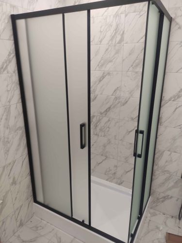 Установлена стеклянная конструкция с черными рамами на поддон, закреплены дверцы, герметизация швов, проверка устойчивости и функциональности, завершение работ в ванной комнате.