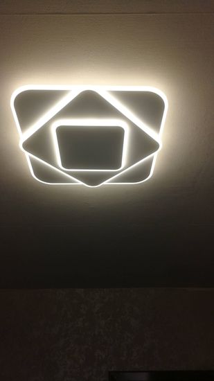 Установлен потолочный светильник с люминесцентными лампами, обеспечивающий равномерное освещение. Компактная конструкция крепко закреплена, подключена к электросети, функционирует исправно.