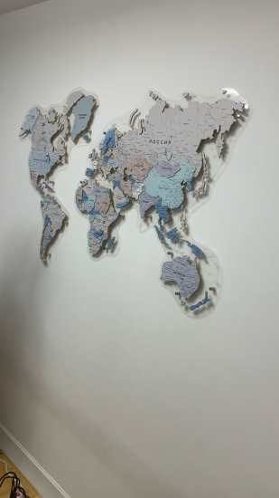 На стене закреплена декоративная карта мира из дерева. Все элементы ровно расположены, надежно зафиксированы. Работа выполнена аккуратно, без видимых повреждений поверхности.